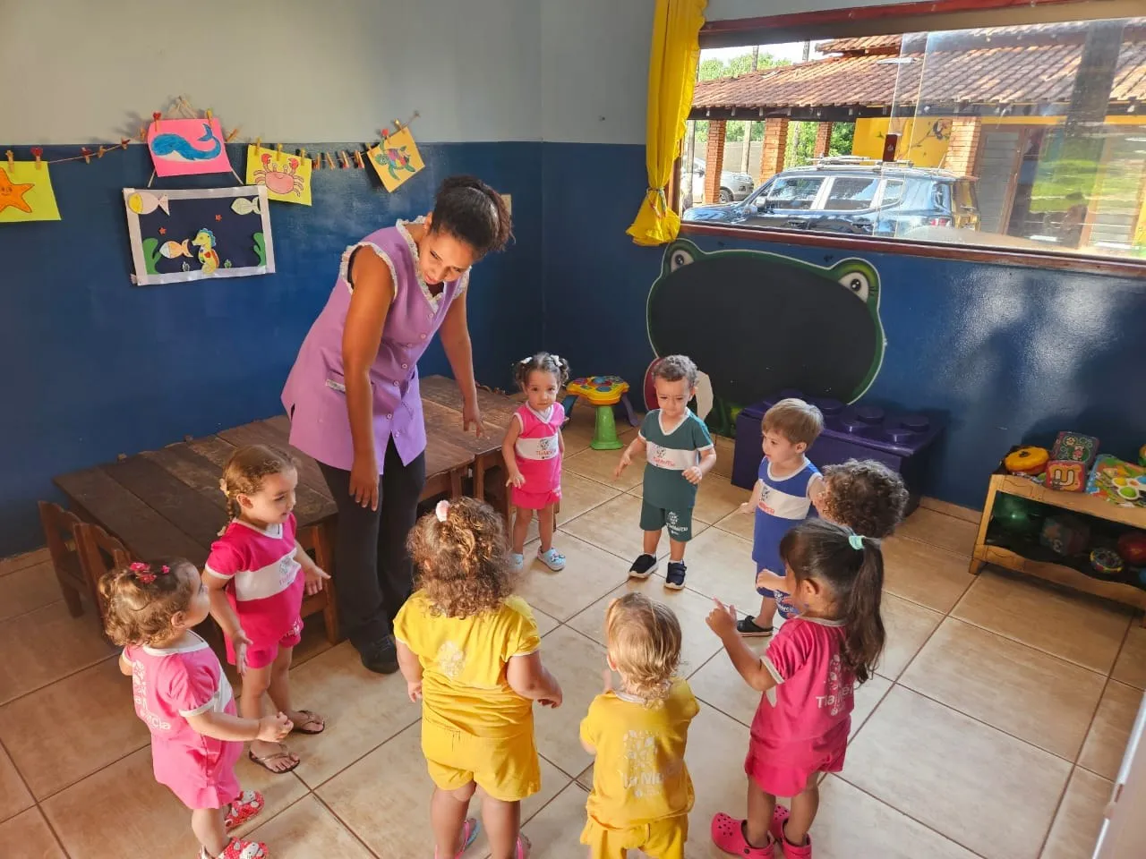 Professora brincando de roda com as crianças pequenas