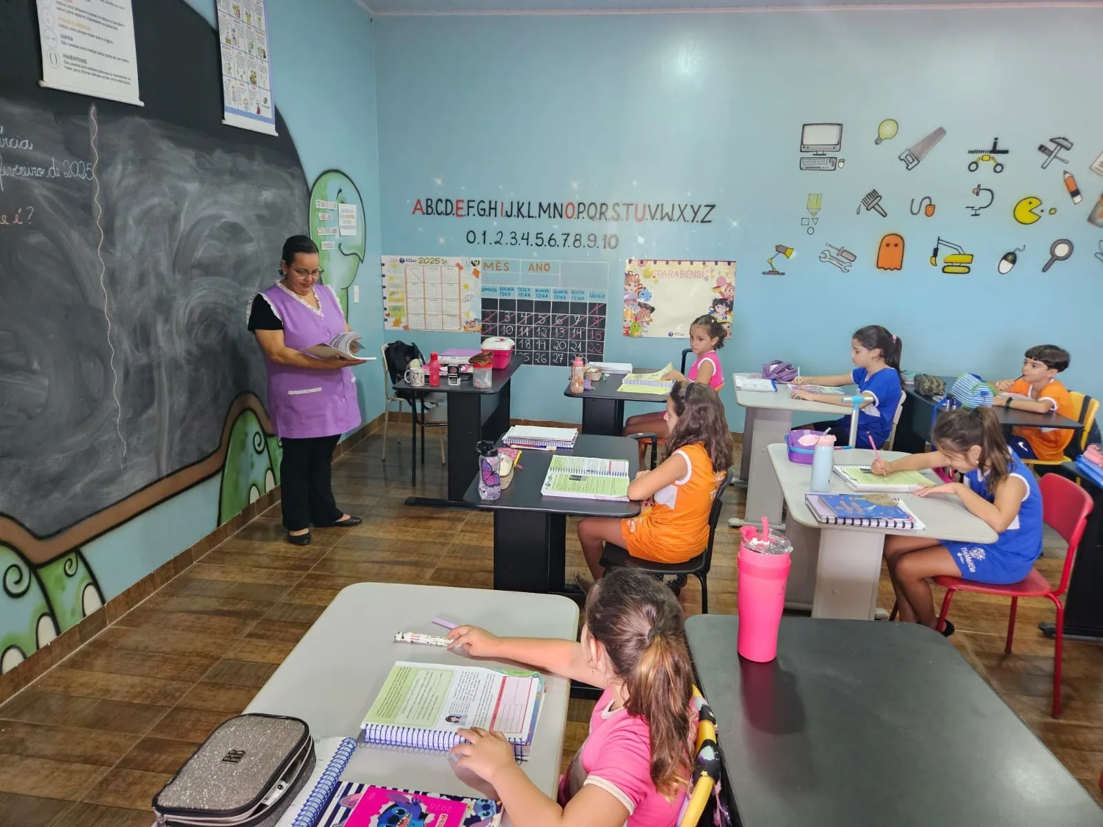 Professora lendo para a turma diante da lousa